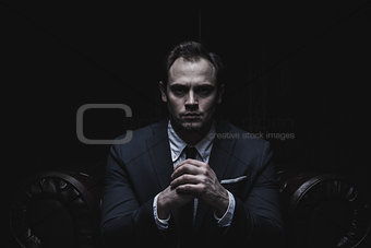 Portrait of a businessman sitting on  armchair  black background