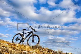 Black bicycle on hill with blue sky background