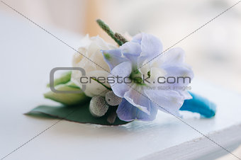 Tender rose and blue flower put in a boutonniere