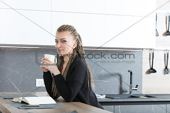 woman in her kitchen reading a book