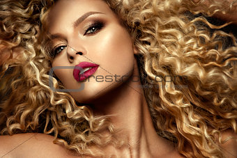 Beautiful face of a fashion model with blue eyes.Curly hair. Red lips.