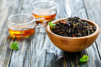 Black tea with flower petals in bowl and cups of hot tea.