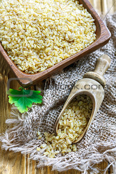 Wooden bowl and scoop with bulgur wheat.