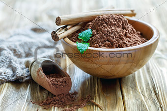 Wooden bowl and scoop with cocoa powder.