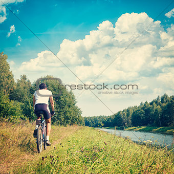 Man Riding a Bike on River Bank. Nature Background