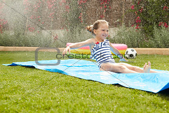 Girl Having Fun On Water Slide In Garden