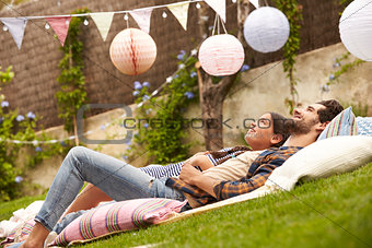 Father With Daughter Relaxing On Rug In Garden Together