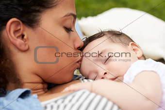 Close Up Of Mother With Baby Relaxing On Rug In Garden