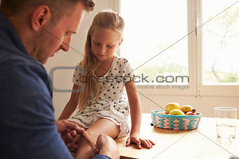 Father Putting Sticking Plaster On Daughter's Knee