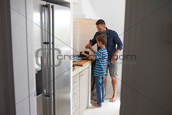 Father And Son In Kitchen Making Meal Together