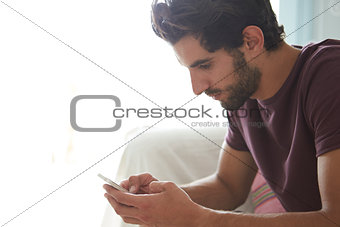 Man Sitting On Sofa Using Mobile Phone To Text Message