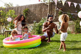 Family Having Fun In Garden Paddling Pool