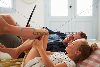 Father And Daughter Lying On Floor Using Digital Tablet