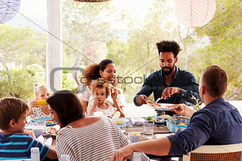Families Enjoying Outdoor Meal On Terrace Together