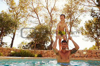 Son Jumping From Father's Shoulders In Outdoor Pool