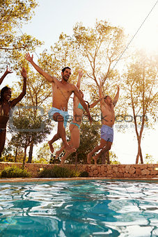 Group Of Friends On Vacation Jumping Into Outdoor Pool