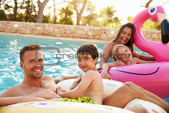 Family On Vacation On Inflatables In Outdoor Swimming Pool