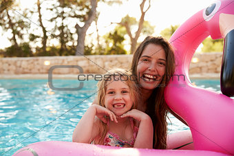 Mother And Daughter On Inflatables In Outdoor Swimming Pool