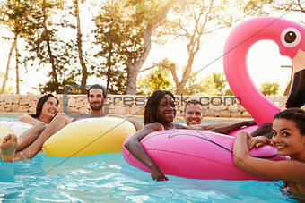 Portrait Of Friends On Inflatables In Outdoor Pool