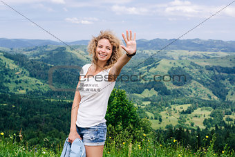 Girl waves her hand in the mountains