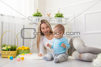 Delighted mother and her child enjoying the Easter egg hunt at home