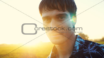 Portrait of man looking at the sun during beautiful sunset with lense flare effects.