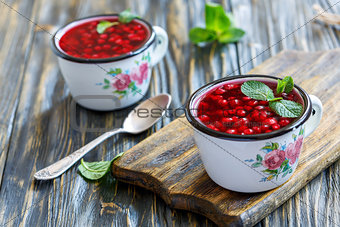 Enamelled mug with cranberry jelly and a teaspoon.