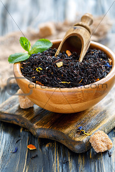Black tea with bergamot and scoop in a wooden bowl.