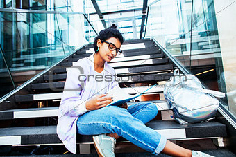 young cute indian girl at university building sitting on stairs