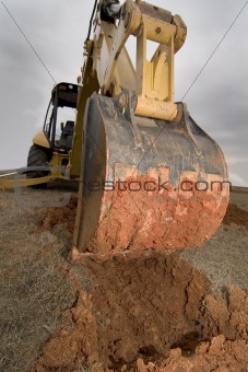 Backhoe digging in red dirt.