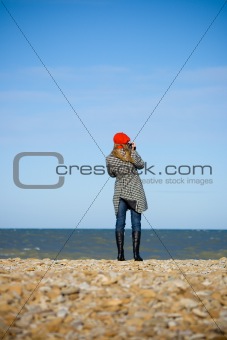 Girl standing on the beach and recording video