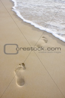 Footprints on beach and wave
