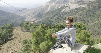 Smiling sportive woman on rock