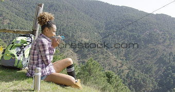 Young woman sitting ground and drinking