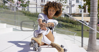 Smiling female sitting on stairs wearing rollerskates