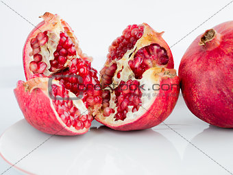Ripe pomegranate fruit on a wite porcelain plate