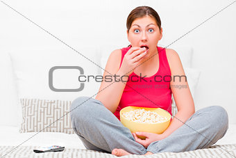 female attentively watching TV and eating popcorn