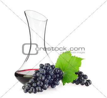 Glass decanter with red organic wine and blue grapes
