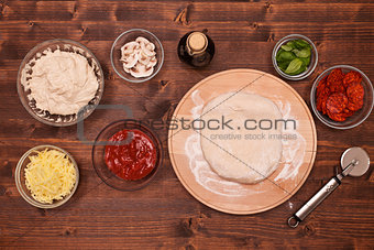 Phases of making a pizza - stretching the dough on wooden plate