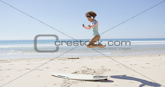 Female listening music and jumping on beach