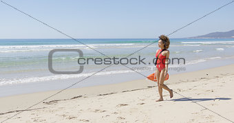 Lifeguard with rescue float walking along beach