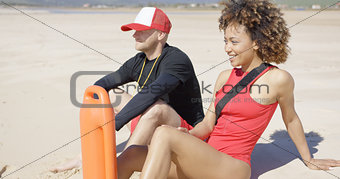 Smiling lifeguards sitting on beach