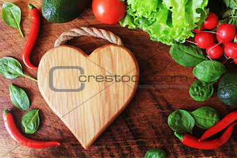 Healthy food ingredients background. Vegetables,herbs and cutting board on wooden background. Top view.