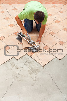 Man cutting ceramic floor tiles with manual cutter