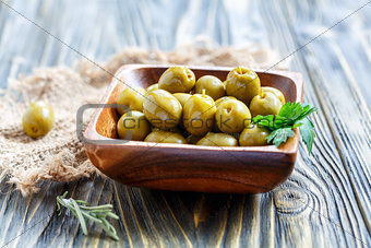 Green olives and parsley in a wooden bowl.