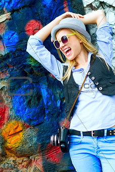 Happy hipster girl looking on copy space against urban wall