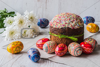 Easter cake kulich with eggs and spring flowers on light wooden background