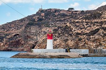 Red and white lighthouse near the fort of Christmas and the seaport. Cartagena, Spain.