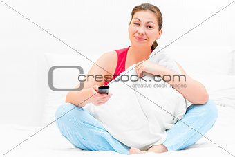 happy woman sitting on the bed watching TV