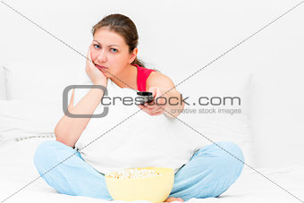 dissatisfied girl in pajamas with a TV remote control